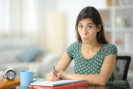 Perplexed student studying looking at camera at homeの写真素材