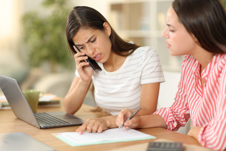 Two tele workers talking on phone claiming contract problem at homeの写真素材