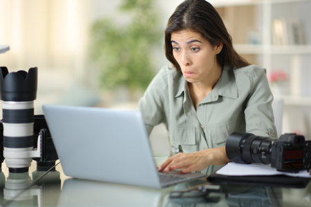 Perplexed photographer checking laptop content working online at homeの写真素材