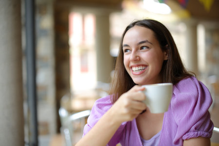 Happy woman drinking coffee and laughing looking away in a bar terraceの写真素材
