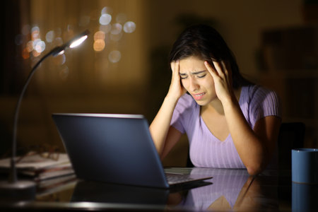 Concerned woman with laptop in the night at homeの写真素材
