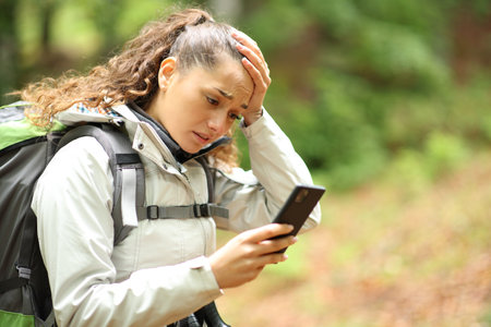 Lost hiker complaining checking cell phone walking in a forestの写真素材