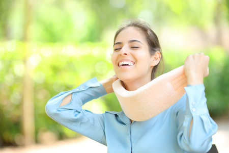 Happy woman taking off neck brace after convalescence in a parkの写真素材
