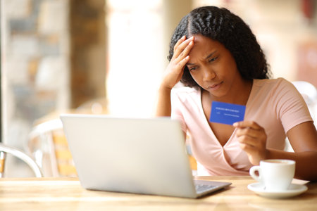 Worried black woman having problem buying online in a coffee shop terraceの写真素材