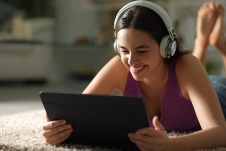 Happy woman watching media on tablet on the floor at homeの写真素材