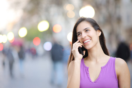 Happy female talking on phone outdoors in the streetの写真素材