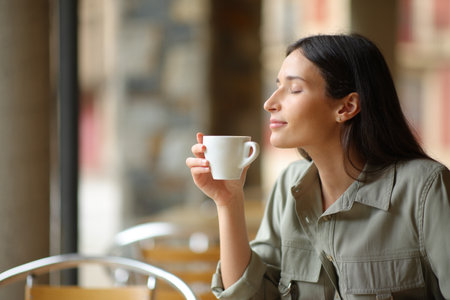 Happy woman smelling coffee in a restaurant terraceの写真素材