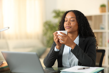 Black freelance worker relaxing drinking and breathing fresh air at homeの写真素材