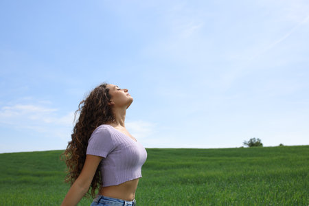 Profile of a casual woman breathing fresh air in a wide fieldの写真素材
