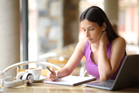 Serious student studying in a coffee shop terrace reading notesの写真素材