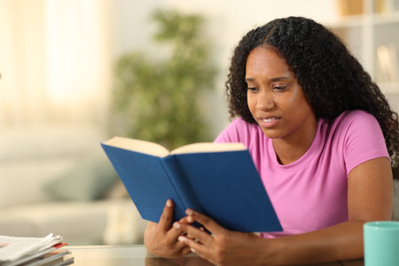 Disgusted black woman reading a paper book at homeの写真素材