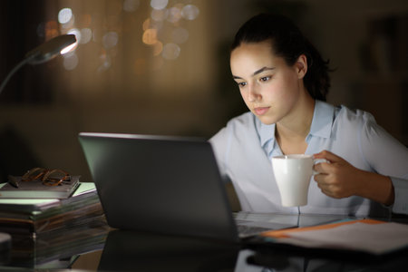 Tele worker working at night and drinking coffee in the darkの写真素材
