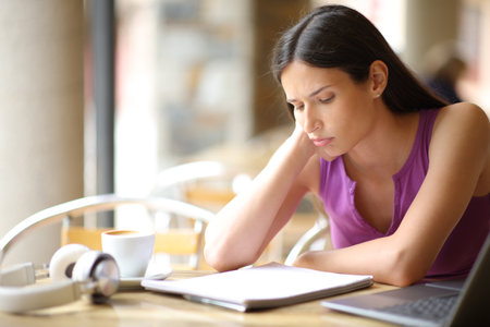 Frustrated student in a bar terrace reading notes trying to learnの写真素材
