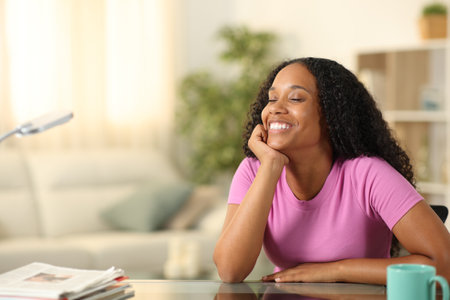 Happy black woman resting breathing and smiling sitting at homeの写真素材