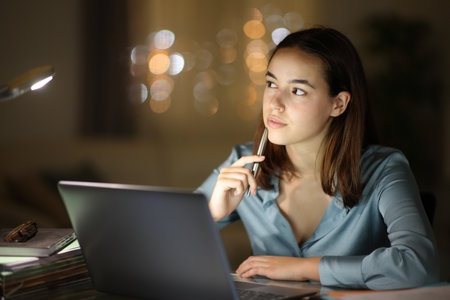 Serious tele worker in the night thinking looking at side and working at homeの写真素材