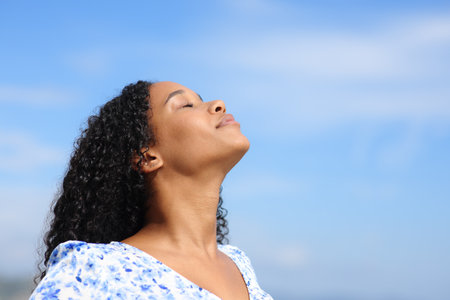 Black woman breathing fresh air with blue sky in the backgroundの写真素材