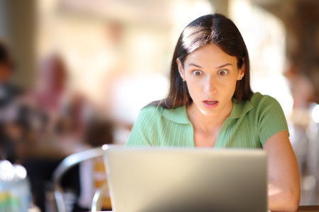 Front view portrait of an amazed woman checking laptop content in a bar terraceの写真素材