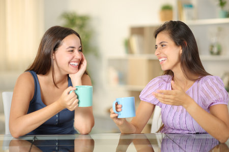 Two friends talking drinking coffee at homeの写真素材