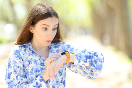 Shocked woman checking smartwatch news outdoorsの写真素材
