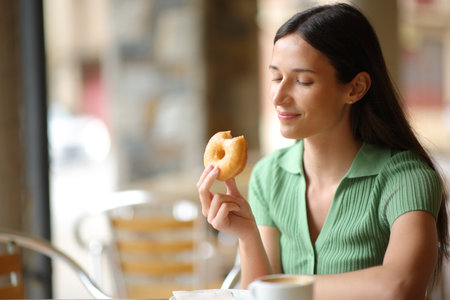 Woman eating donut in a restaurant terraceの写真素材