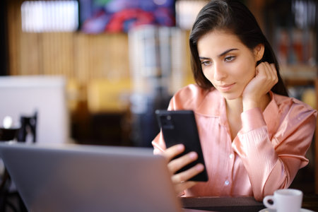 Freelance worker using multiple devices and checking phone in a barの写真素材