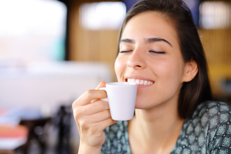 Happy woman smelling coffee from cup in a restaurant interiorの写真素材