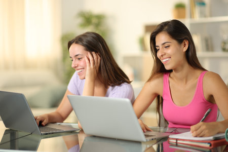 Happy students learning online with laptops at homeの写真素材