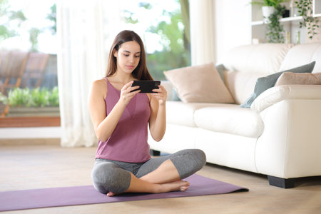 Yogi watching online yoga tutorial on phone ready to exercise at homeの写真素材