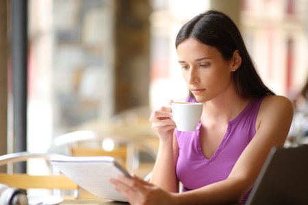 Student learning reading notes drinking coffee in a restaurant terraceの写真素材