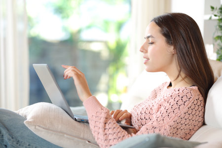 Side view portrait of a woman is using laptop sitting at homeの写真素材