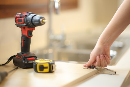 Woman hand assembling kitchen furniture in the kitchen at homeの写真素材