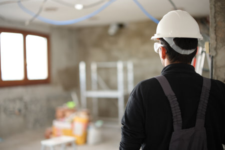 Back view portrait of a construction worker looking at site under renovationの写真素材