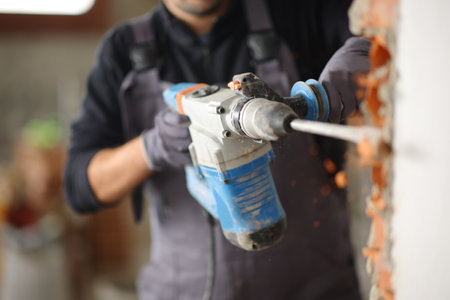 Close up of a construction worker using rotary hammer to wreck wall in a house under renovationの写真素材