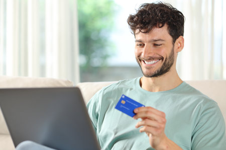 Happy man buying online with laptop and credit card at homeの写真素材