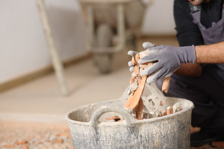 Close up of a construction worker hands removing debris to a carrycot in a house under renovationの写真素材