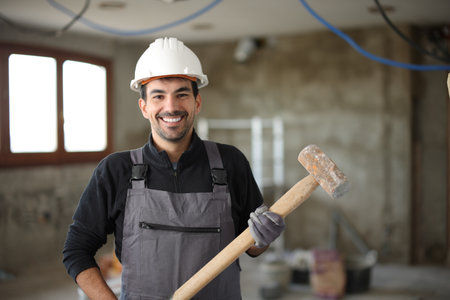 Front view portrait of a happy construction worker posing in a house under renovation