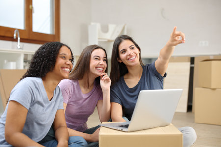 Three happy women planning decoration moving house pointing awayの写真素材