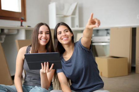 Two happy roommates planning renovation in the kitchen while moving houseの写真素材