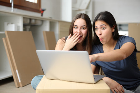 Amazed roommates checking laptop surprising news reforming houseの写真素材