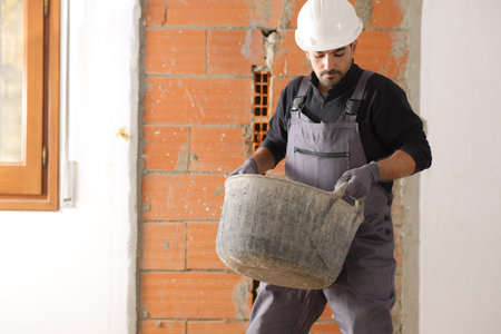 Construction worker is lifting a heavy carrycot in a house under renovationの写真素材