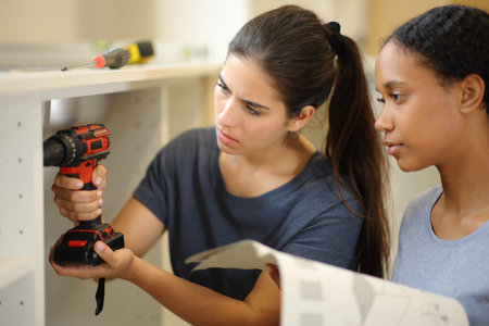Interracial roommates installing furniture in the kitchen with instructions manualの写真素材