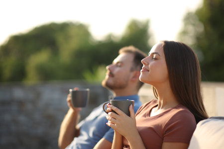 Couple drinking coffee and breathing fresh air sitting on a terraceの写真素材
