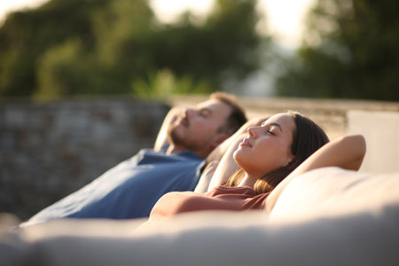Couple resting and relaxing sitting on a couch in a terrace at homeの写真素材