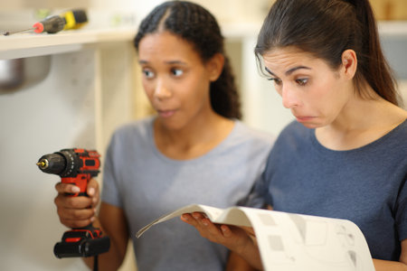 Two perplexed roommates installing furniture reading manual renovating homeの写真素材