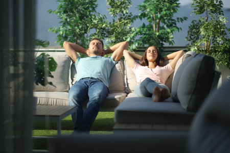 Front view of a couple relaxing on a couch in a terraceの写真素材
