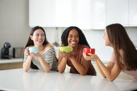 Three roommates drinking coffee and talking in the kitchen at homeの写真素材