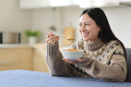 Asian woman in winter eating cereals for breakfast in the kitchen at homeの写真素材