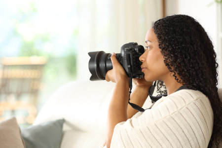 Black woman photographing with camera through a window at homeの写真素材