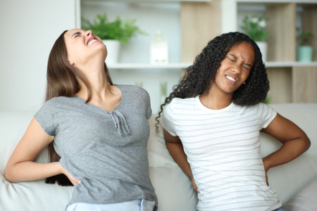 Couple suffering back ache on uncomfortable couch complaining at homeの写真素材