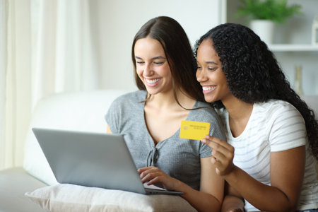 Happy couple buying online with laptop and credit card at homeの写真素材